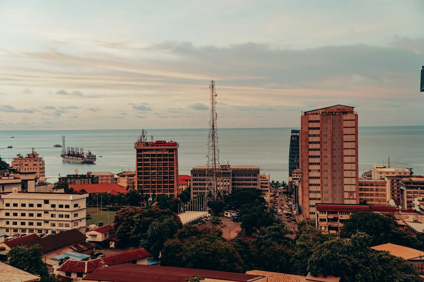 Central Freetown at dusk, looking out over the Atlantic, with a communications tower rising between the office blocks